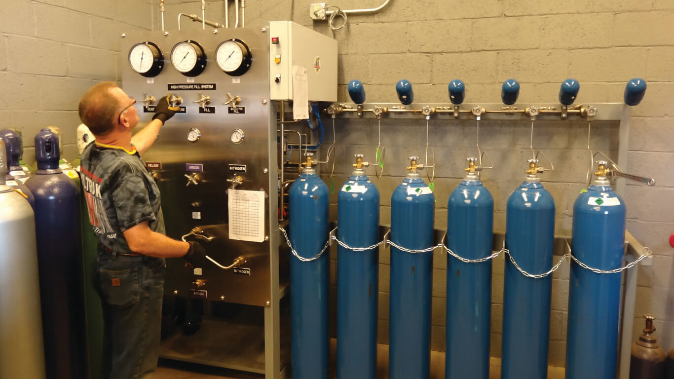 man at a control station filling various gas cylinders