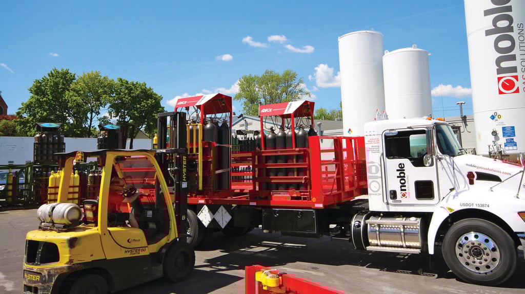 gas cylinders in Weldcoa gas pallets being loaded on a truck with a forklift