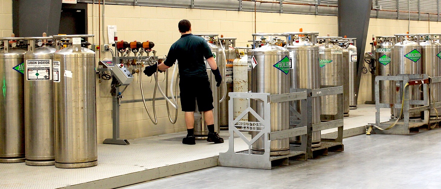 man filling various large gas cylinders 