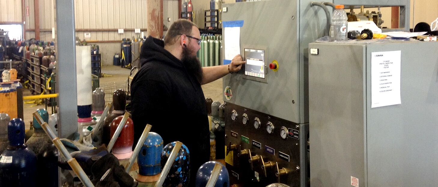 man using a control panel to fill gas cylinders