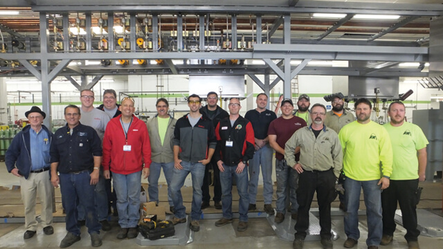 Cee Kay Employee group photo in front of cylinder filling equipment