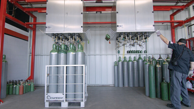 Man filling gas cylinders using a Weldcoa automated industrial fill system