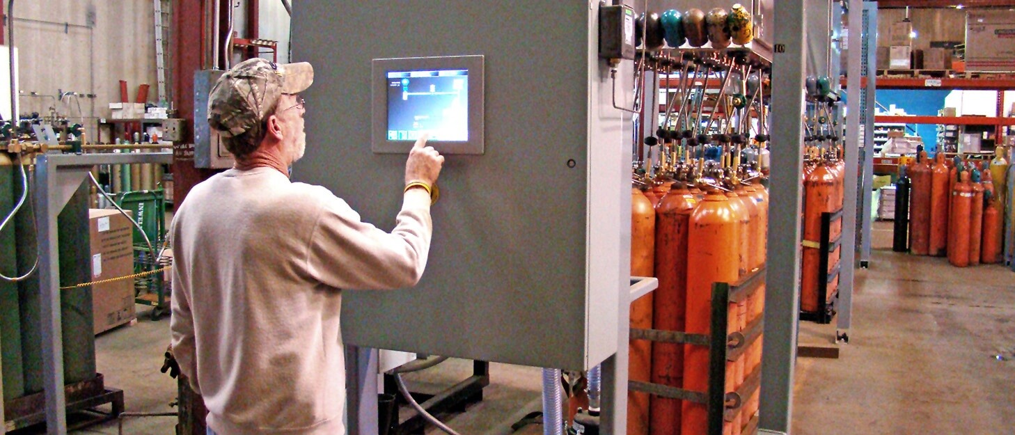 man using a control panel to fill gas cylinders at a American Welding & Gas filling plant