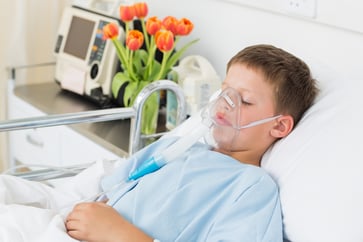 Sick little boy wearing oxygen mask in hospital ward Sick little boy wearing oxygen mask in hospital ward
